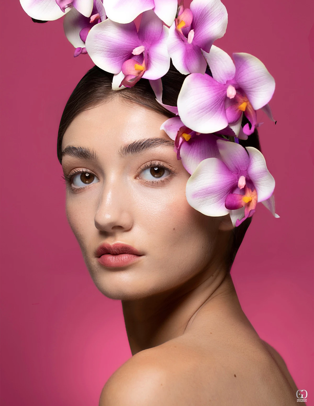 Beauty portrait with purple orchids against a berry-colored background