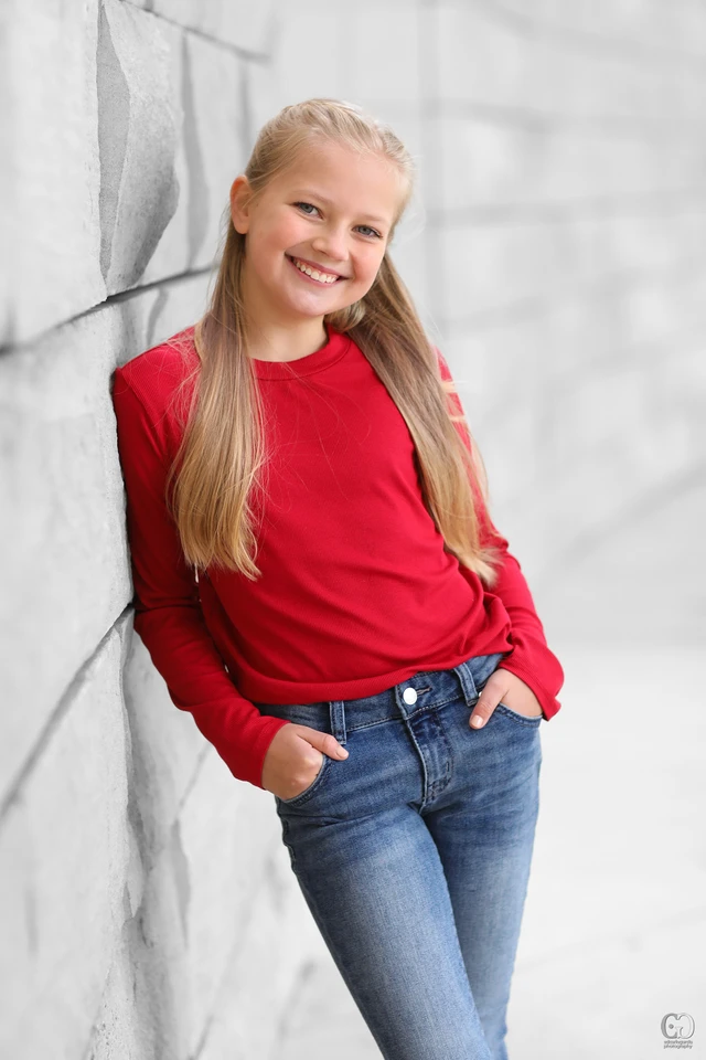 Young model in a red top against a stone wall