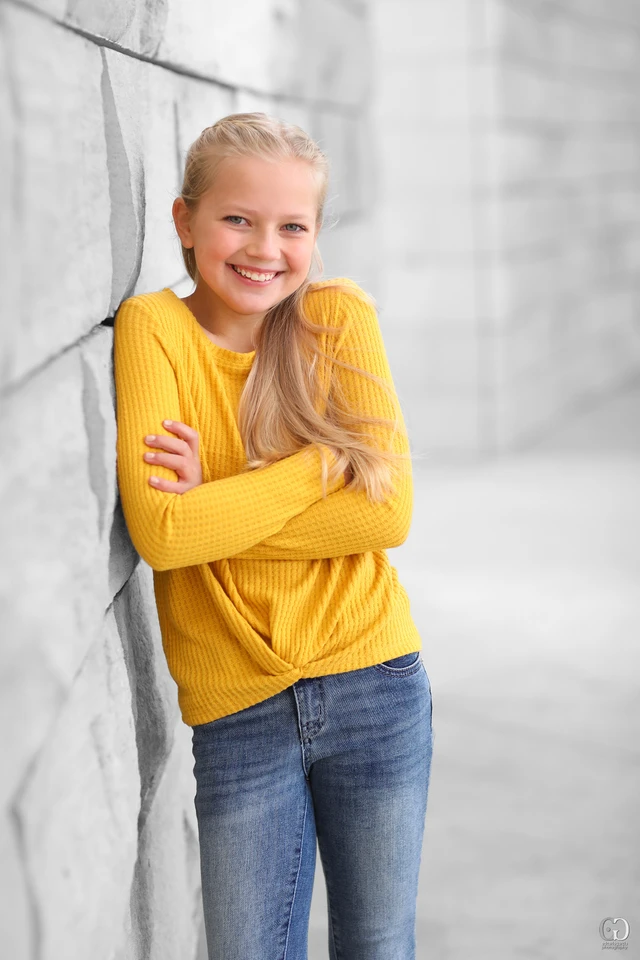 Young model in a yellow sweater against a stone wall